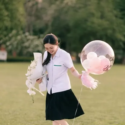 บัณฑิตถือช่อดอกไม้และลูกโป่งในสวน ถ่ายรูปรับปริญญานอกรอบ