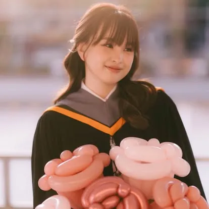 บัณฑิตชุดครุยกับลูกโป่งและตุ๊กตา